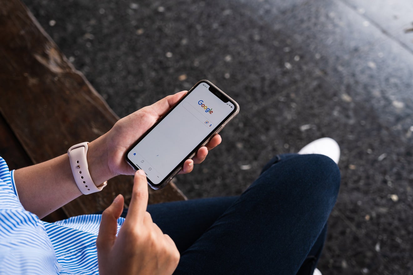 Google Search Ads person using Google on phone while sat on a bench
