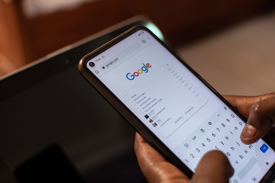 Google September volatility (1) Hands holding a mobile device showing the Google homepage with a search query
