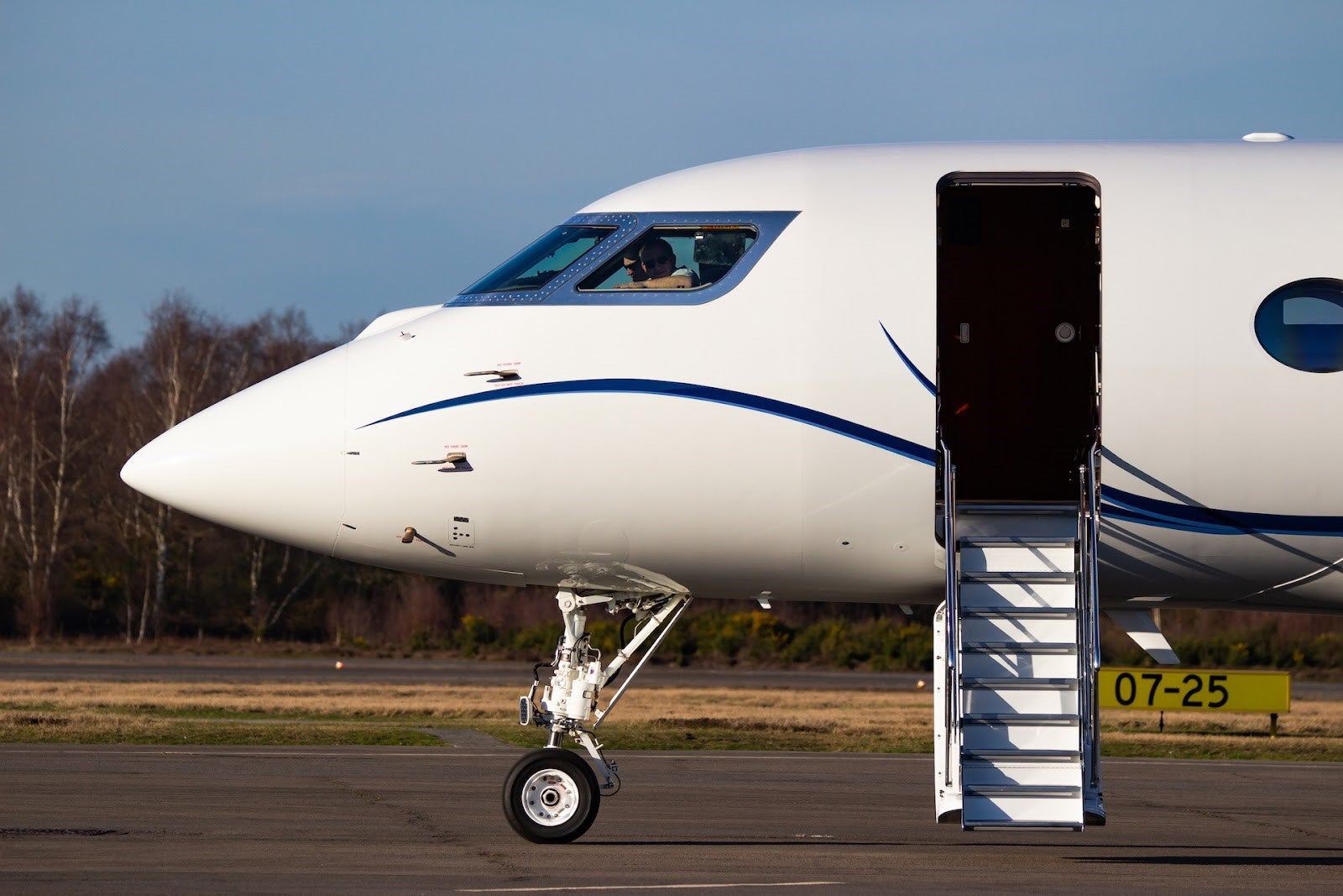Lux Jets image 1 the cockpit of a hit private jet on a runway with stairs leading inside