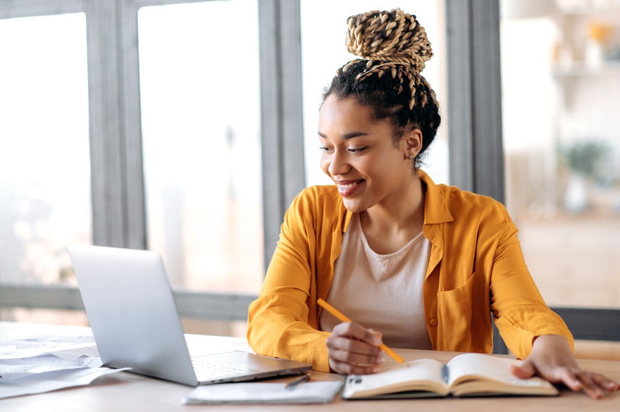 Online SEO courses August Woman working on a table and smiling at her laptop