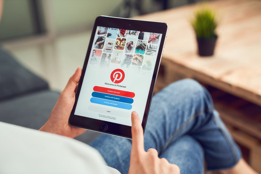 Pinterest Inclusion Fund Person sat holding a tablet with the Pinterest login page on the screen