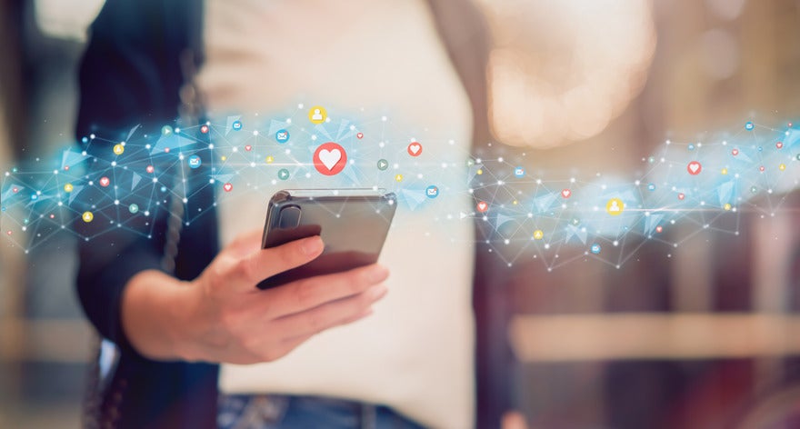 Social media newsletters Person holding mobile phone with stream of social media icons flowing above it