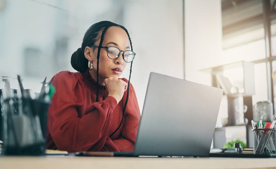 What is forking Woman sat and looking focused at the laptop in front of her